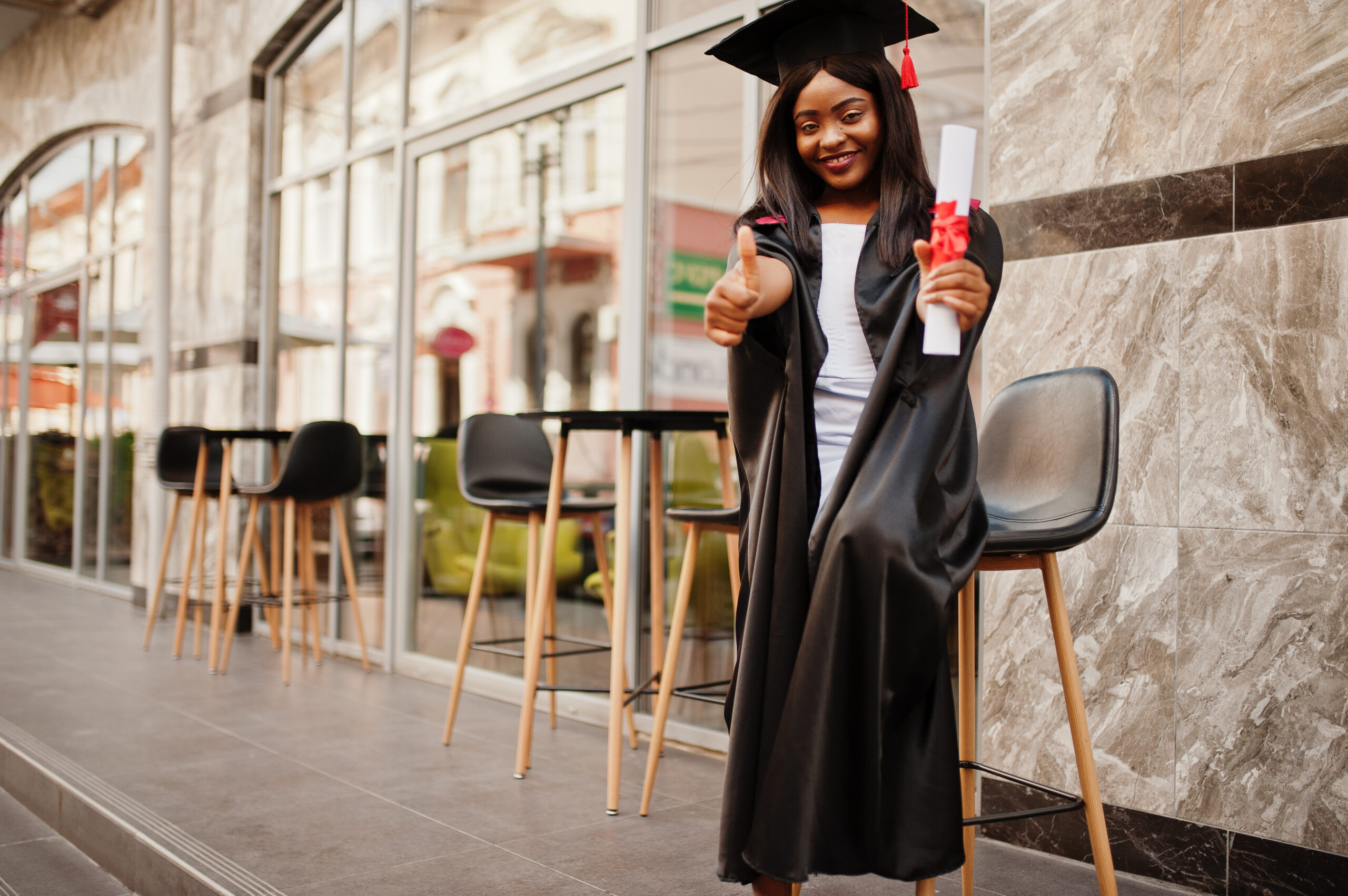 young female african american student with diploma poses outdoor
